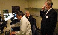 A set of images of Tariq Ashkanani and Clara Calvert showing two men, possibly named "Tam" and "Prin", a chemistry lab containing 3D glasses, a microscope, pipettes and unknown sample.  5 images.
